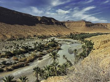 River runing through arid countryside. date palm trees.