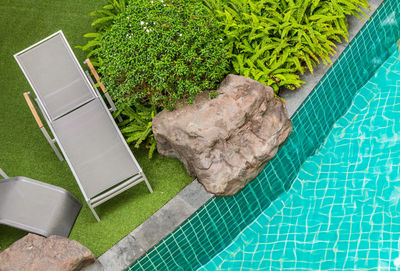 High angle view of lounge chair by swimming pool