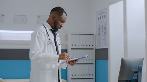 Side view of doctor looking at clipboard in clinic