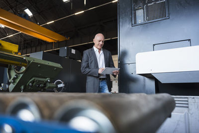 Man with tablet at machine on factory shop floor