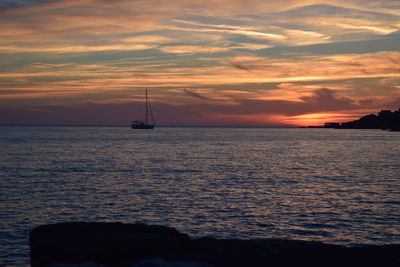 Silhouette sailboat sailing on sea against sky during sunset