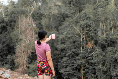 Side view of woman standing on mobile phone