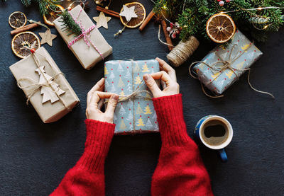 Elegant female hands tying twine on a wrapped christmas present. festive layout