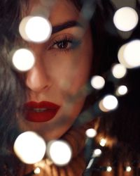 Close-up portrait of young woman with illuminated christmas lights