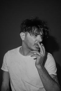 Portrait of young man looking away against black background