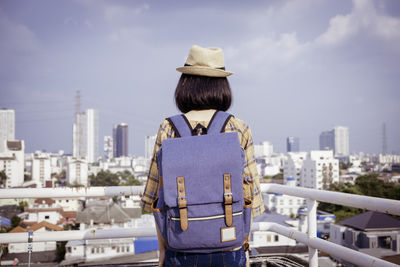 Rear view of woman looking at cityscape against sky