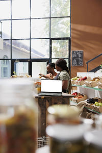 Rear view of woman using laptop on table