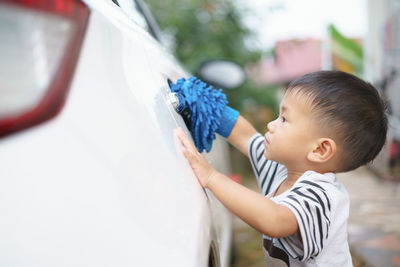Cute boy cleaning car
