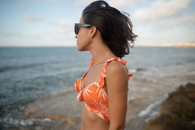 Young woman wearing sunglasses standing on beach