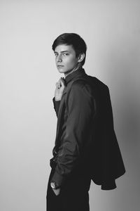 Portrait of young man standing against wall