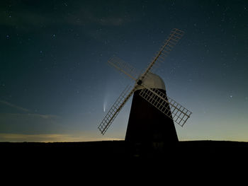 Traditional windmill on field against sky at night with comet neowise