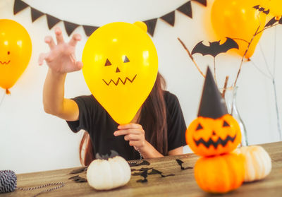 Woman covering face with balloon during halloween celebration