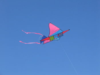 Low angle view of kite flying against clear blue sky