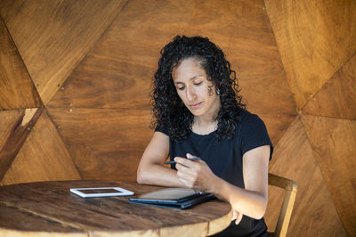 Woman using a digital tablet while sitting at a table.