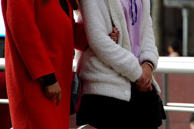 Midsection of female friends wearing warm clothing in city