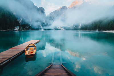 From above wooden quay on amazing scenery of lake with turquoise water in mountains on foggy day