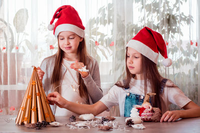 Christmas handmade. girls glue stars on a handmade paper tree and prepare a garland