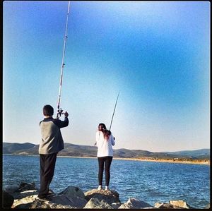 Full length of man fishing at beach against clear sky