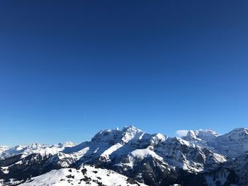 Scenic view of snowcapped mountains against clear blue sky