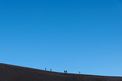 Low angle view of people standing on mountain against sky