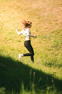 Side view of girl running on grassy field