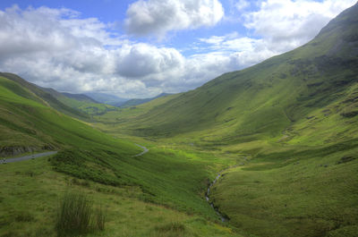 Scenic view of green landscape and mountains against sky