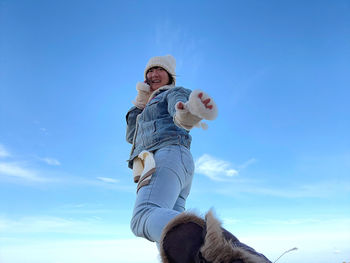 Low angle view of woman standing against blue sky