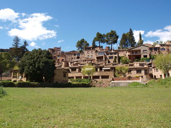 Houses on field by buildings against sky