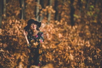 Young woman standing amidst leaves in field