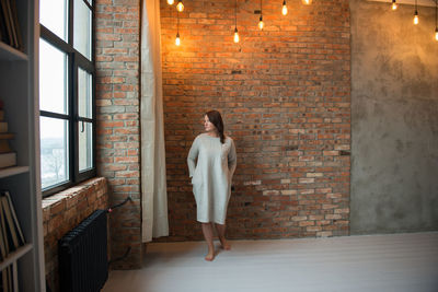 Rear view of woman standing against window