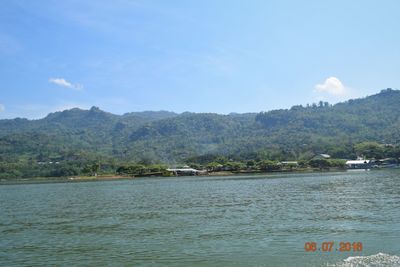 Scenic view of sea by mountains against sky