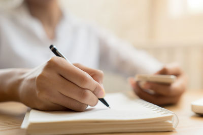 Midsection of woman reading book on table