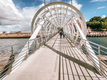 People on bridge over river against sky