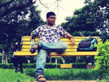 Portrait of man sitting on bench in park