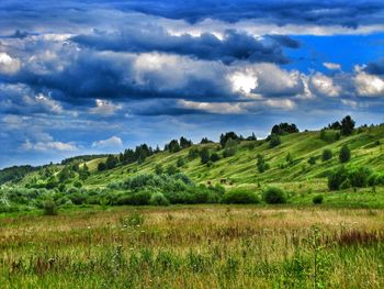 Scenic view of grassy field against cloudy sky