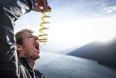 Man eating apple after using apple peeler at sunset above sea squamish