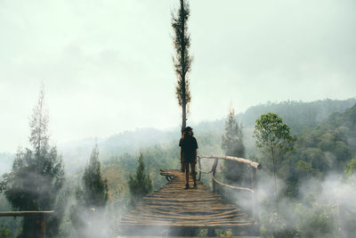 Woman  standing on footbridge against sky