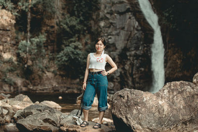 Portrait of young woman standing on rock outdoors