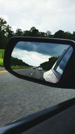 Reflection of clouds in side-view mirror