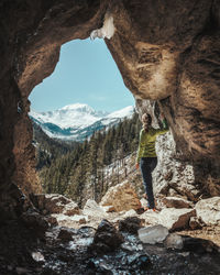 Rear view of woman standing on rock in cave