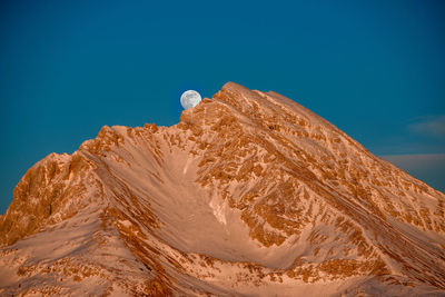 Snow-capped mountain with rising moon