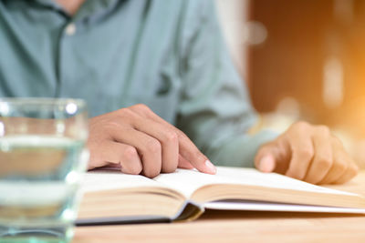 Midsection of man reading book on table