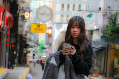 Young woman using mobile phone in city during winter