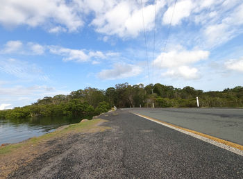 Road by trees against sky