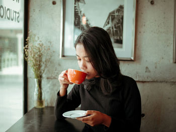 Full length of a woman drinking coffee