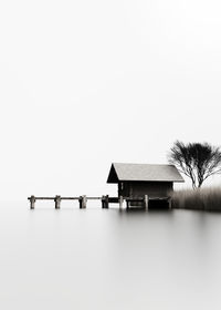 House by lake against clear sky