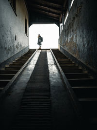 Rear view of man walking on staircase of building