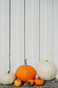 Pumpkins on table against white wall