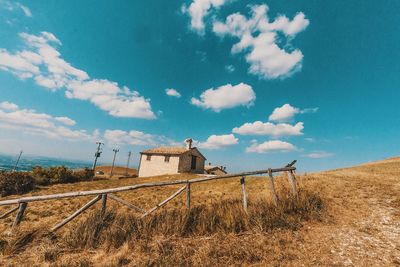 Log cabin on grassy field against sky