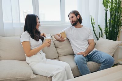 Couple using phone while sitting on sofa at home